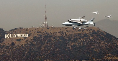 Seen from the US Bank Tower in downtown Los Angeles, the space shuttle Endeavor passes the Hollywood sign as the retired space shuttle makes the rounds of the Los Angeles and Orange County areas before landing at LAX.